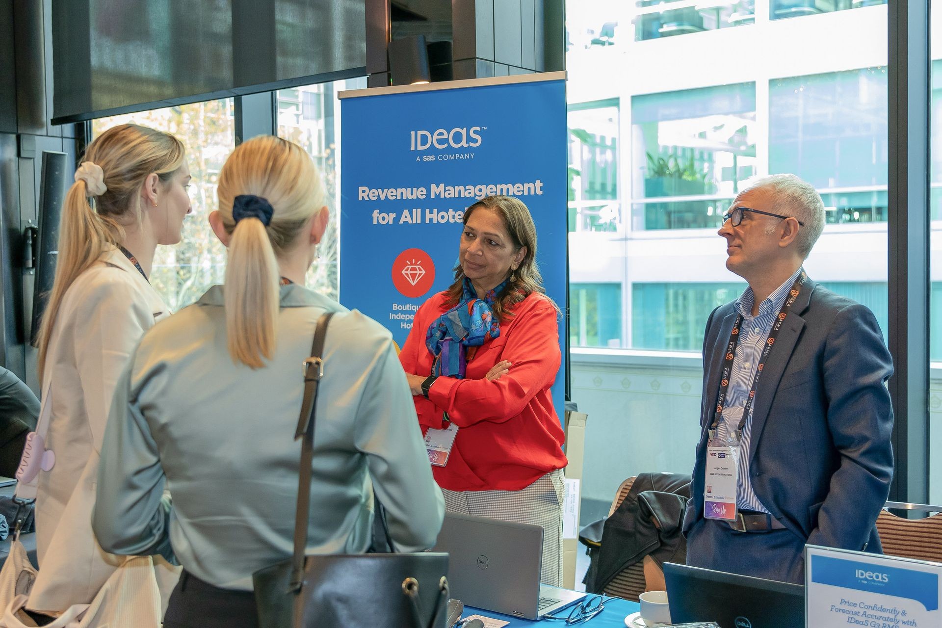 People conversing at a booth with a banner advertising revenue management for hotels.